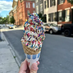 Soft server twist with rainbow sprinkles and fruity pebbles ice cream in the cone