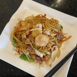  a plate of noodles with shrimp and vegetables
