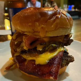 a burger with bacon, cheese, and onions