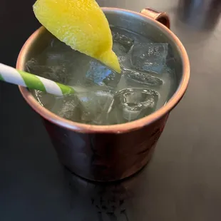 a drink in a copper mug with ice and a lemon wedge