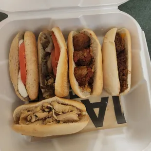 four hot dogs in a styrofoam container