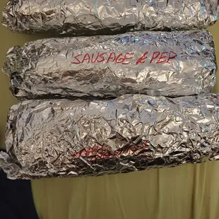 three wrapped sandwiches on a plate