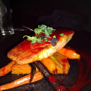 Salmon with orange sauce served over carrots and a chickpea cake