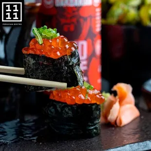 a sushi roll with red cavia and chopsticks