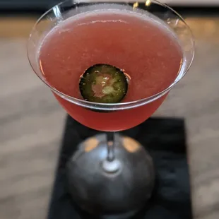 a pink drink with a slice of jalapeno