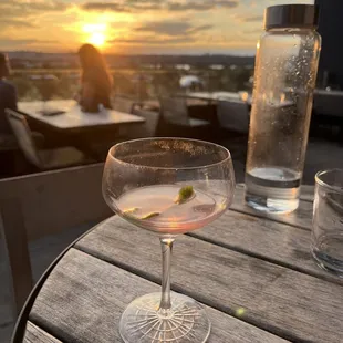 a drink on a table with a sunset in the background