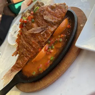 a plate of fish with sauce and vegetables