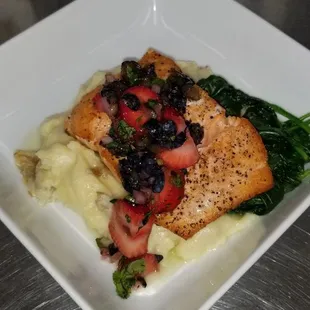 a white square plate with a piece of salmon, mashed potatoes, and spinach