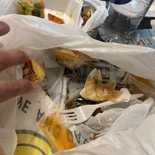 a person grabbing a sandwich from a plastic bag