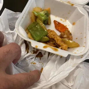 a hand holding a container of food