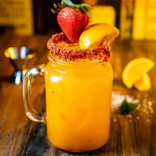 a glass of orange juice with a strawberry on top