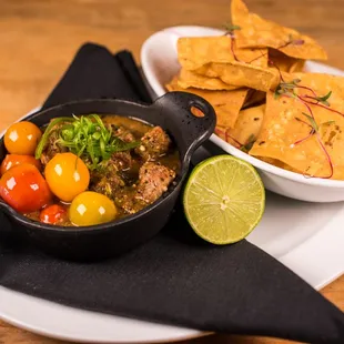 a bowl of chili, tomatoes, and tortillas