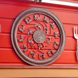a red wall with a circular medallion and spoon and fork