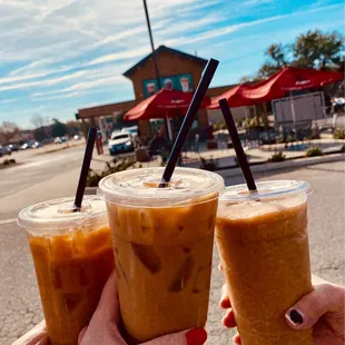 two people holding iced coffees