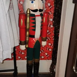 a nutcracker standing in front of a red wall