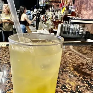 a glass of lemonade sitting on a bar