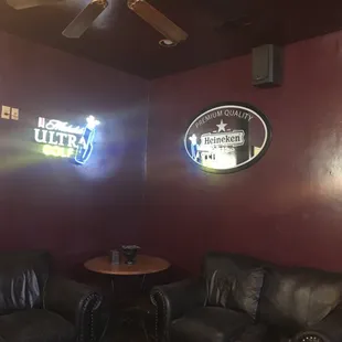 two leather couches and a neon sign