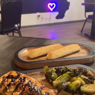 One of the signature dishes. (Appears to be grilled chicken, smashed brussel sprouts, &amp; breadsticks)