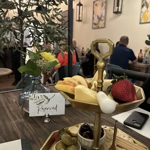 a platter of cheese, crackers, olives, and strawberries