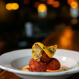 a plate of meatballs with lemon wedges