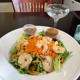 a plate of salad with shrimp and carrots