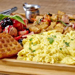 Brunch Charcuterie Board with waffle battered chicken, candied bacon, sausage, house potatoes &amp; scrambled eggs. Served with churro waffles
