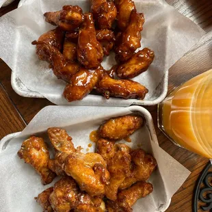 two baskets of chicken wings and a glass of orange juice