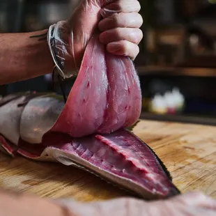 a person slicing meat on a cutting board