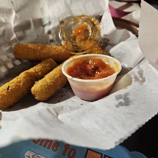 a basket of deep fried breadsticks and a cup of ketchup