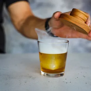 a person squeezing a glass of beer