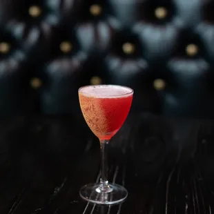 a cocktail in a wine glass on a wooden table