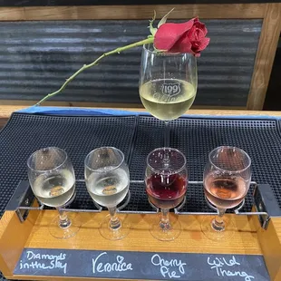 four glasses of wine and a rose