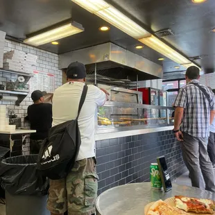 a man standing in front of a pizza counter