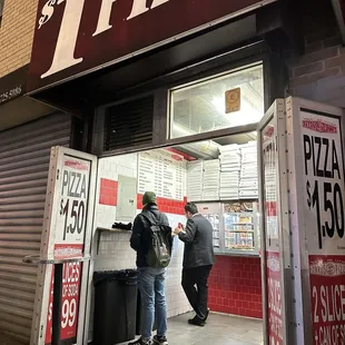 two men standing in front of a pizza parlor