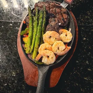 a skillet with shrimp and asparagus