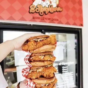 a person holding a stack of fried chicken sandwiches