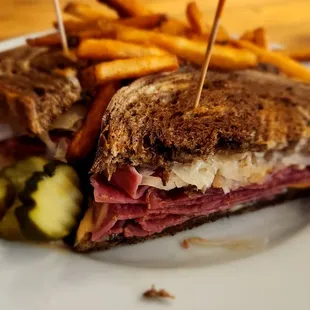 A Reuben Sandwich with pickles &amp; fries