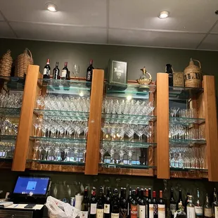 a bar with wine glasses on the shelves