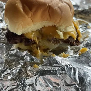 a cheeseburger sandwich on aluminum foil