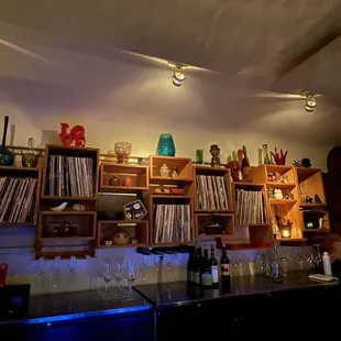 a bar with a shelf of records and wine glasses
