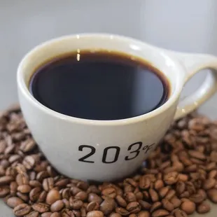 a cup of coffee surrounded by coffee beans