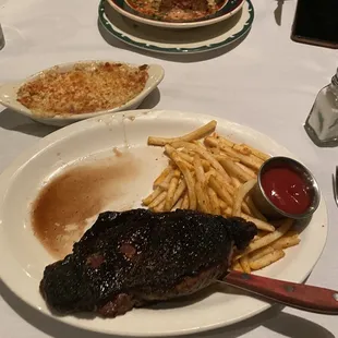 New York Ancho Strip with shoe string fries +21 Mac &amp; Cheese Eggplant Parmesan with Veal Meatballs in the background