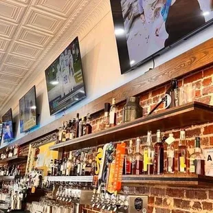 a bar with a brick wall and televisions