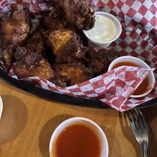 a basket of chicken wings and dipping sauces