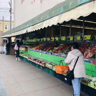 people shopping at a fruit and vegetable stand