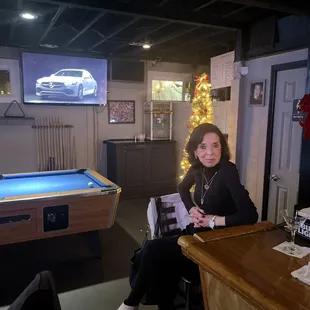 a woman sitting at a bar with a pool table