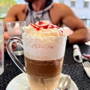 a cup of coffee with whipped cream and strawberries