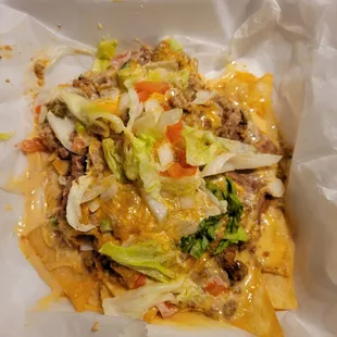 a plate of nachos with meat and vegetables