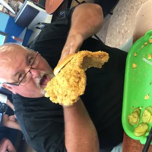 a man eating a piece of fried chicken