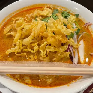 a bowl of soup with chopsticks